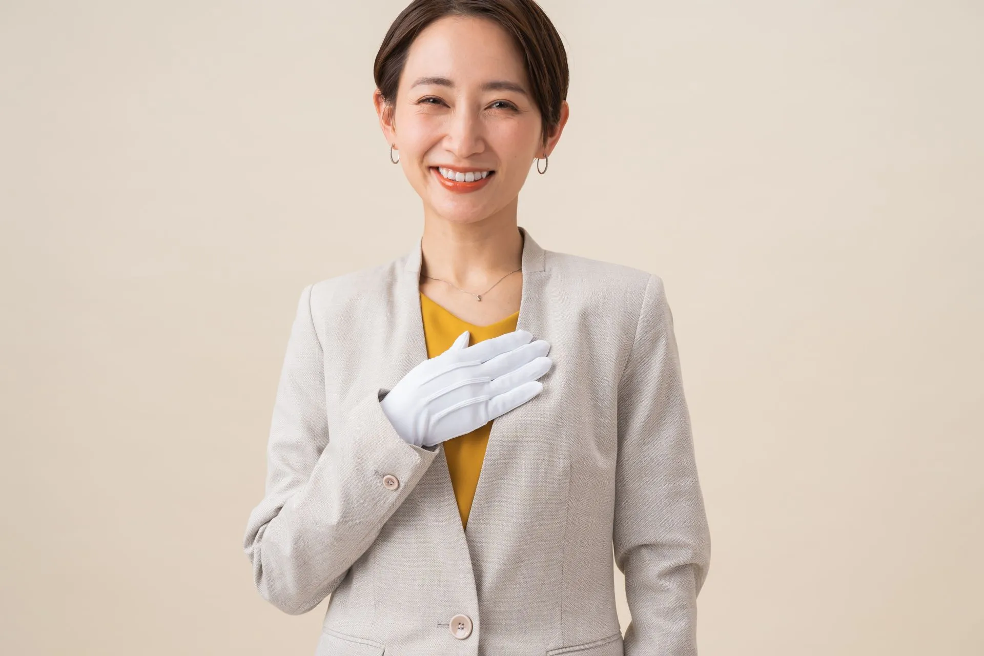 正面を向いて笑顔で胸に手を当てている女性